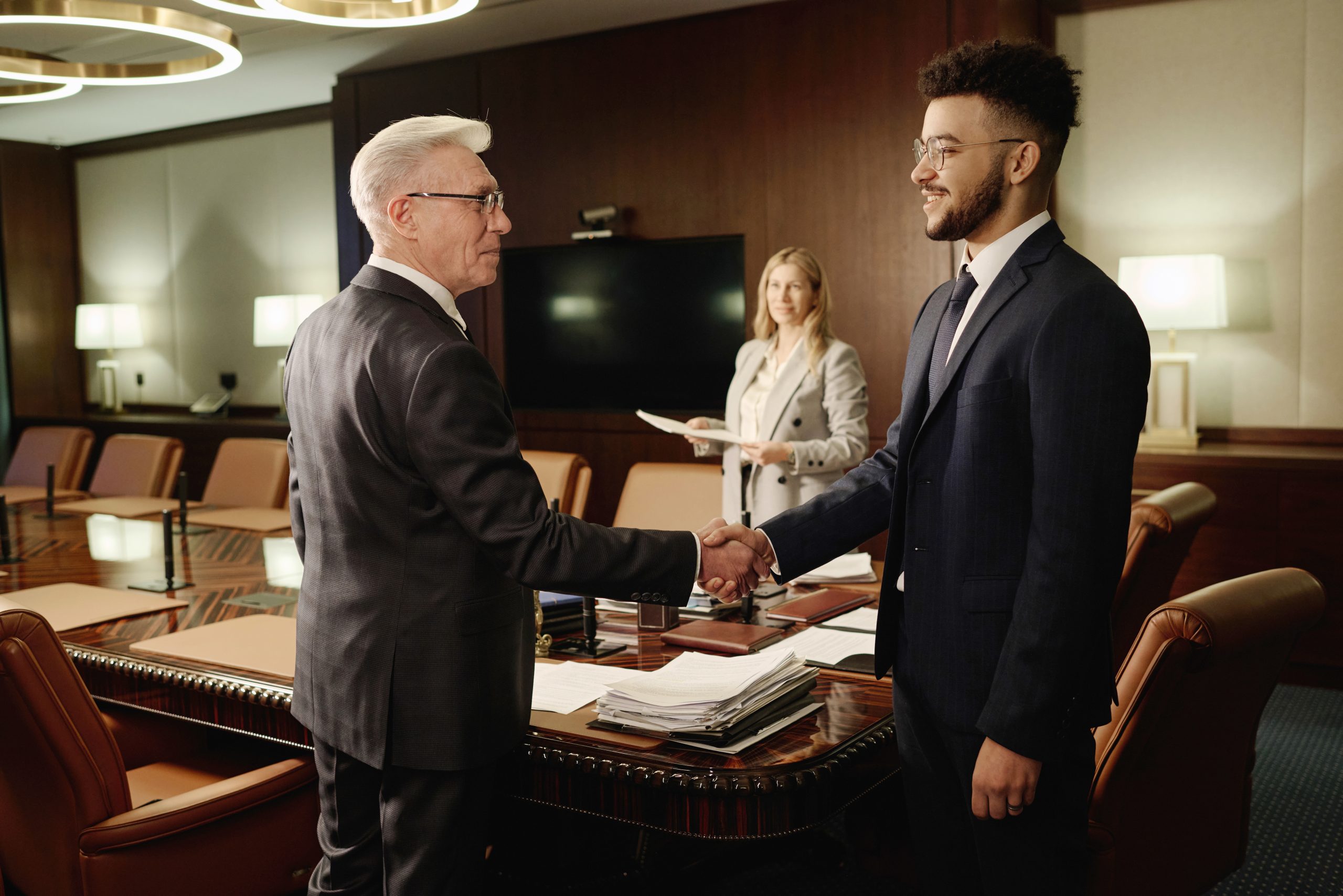 Caucasian and Middle Eastern Men Shaking Hands Standing in Office Boardroom - Ingénierie Pédagogique